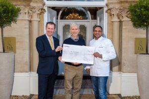 Michael Caines holding cheque for Down Syndrome International and Association