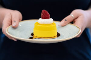 lemon and raspberry cake on plate held by hands
